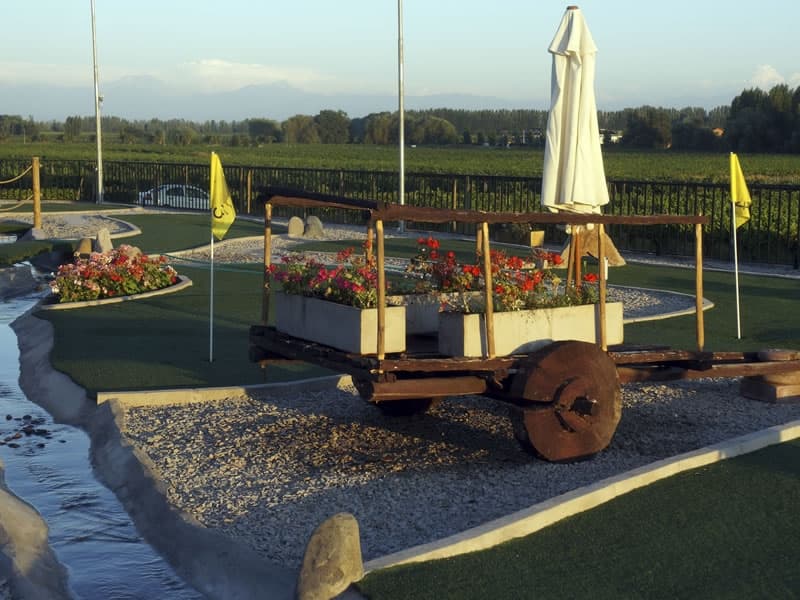 Mini golf al atardecer, con una carreta con flores y la cordillera al fondo